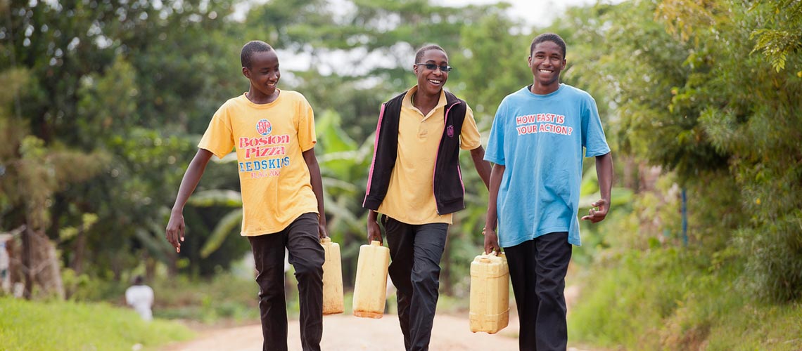 Boys in Uganda walking with clean water