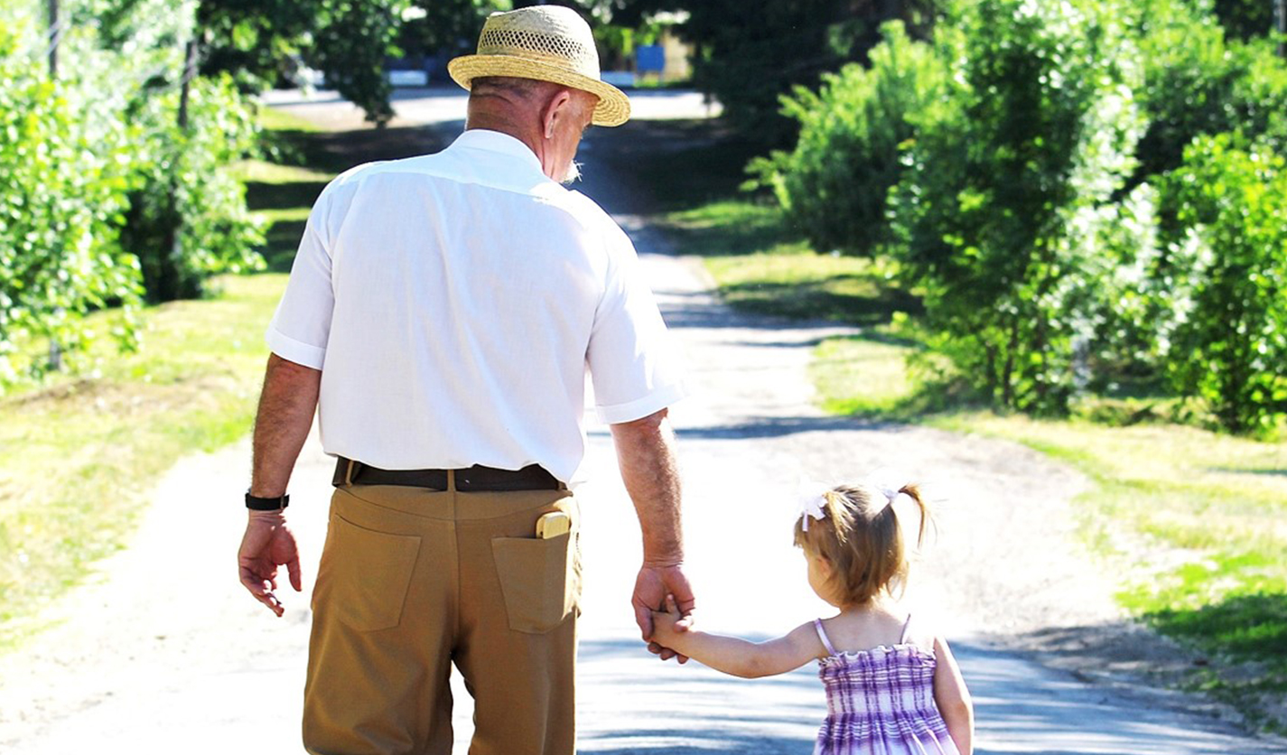 grandfather walking with granddaughter on gravel path