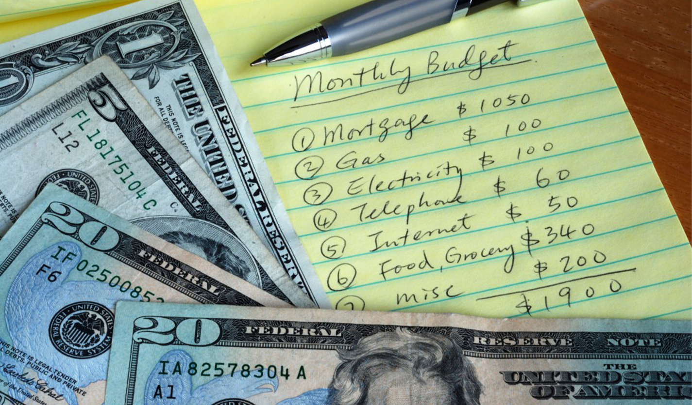 Monthly Budget list with a pen and cash money.
